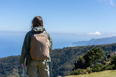 Woman with a backpack taking in the view of a coastal landscapeの写真素材