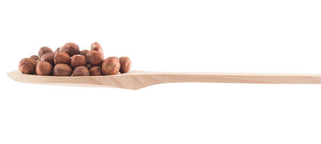 Wooden spoon full of hazelnuts isolated over white background, side view