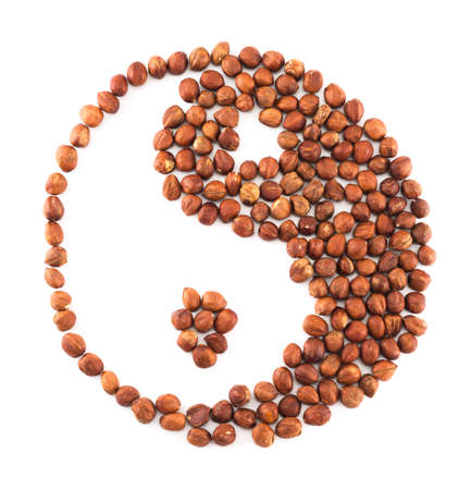 Yin-yang shape composition made of hazelnuts isolated over white backgroundの写真素材