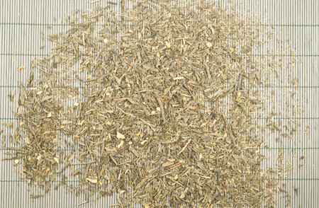 Green tea leaves over bamboo mat as abstract background top view