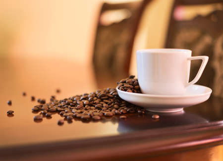 Cup of fresh coffee with the roasted beans on the table as a home interior backgroundの写真素材