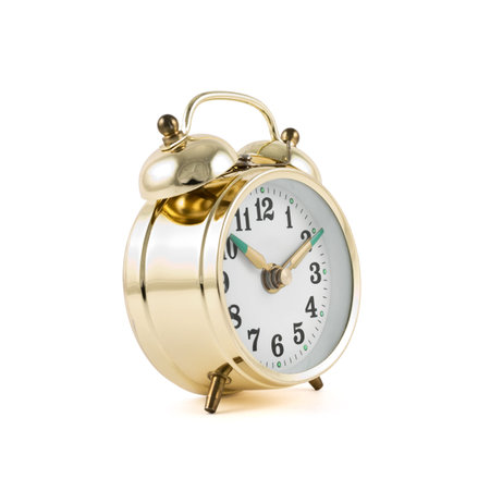 Traditional wind-up keywound, spring-driven mechanical golden alarm clock isolated over white...