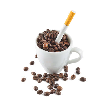 Coffee and tobacco  cigarette in a cup full of beans isolated over white backgroundの写真素材