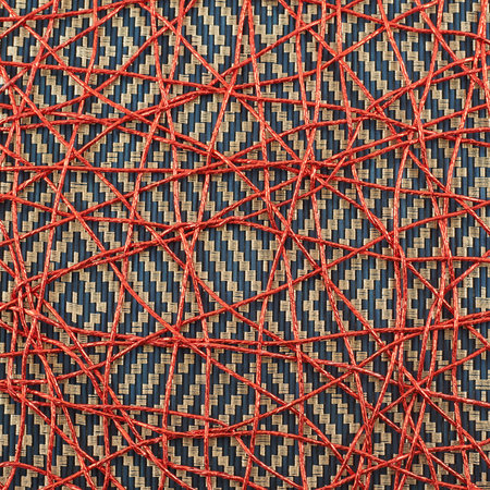 Bamboo mat covered with the red threads as abstract background composition