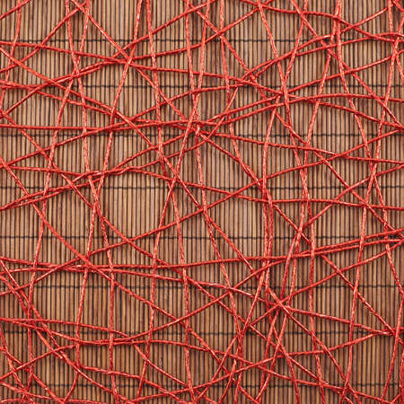 Bamboo mat covered with the red threads as abstract background compositionの写真素材