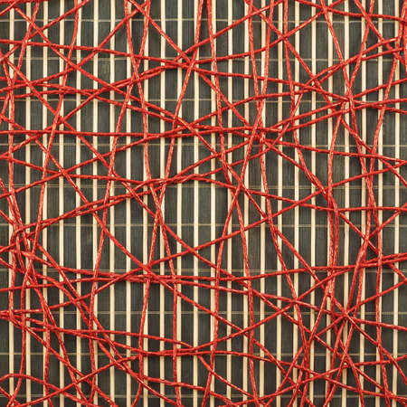 Bamboo mat covered with the red threads as abstract background compositionの写真素材
