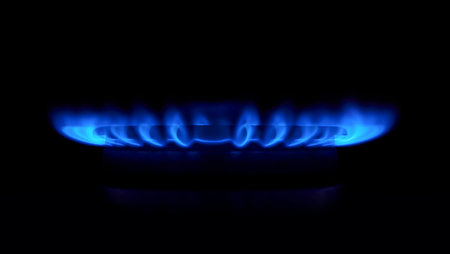 Gas stove as a blue fire lights in the dark