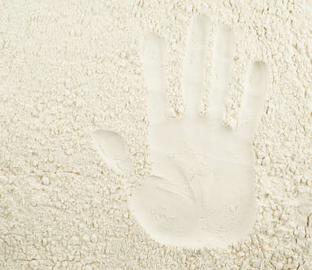 Handmade baking concept as a hand imprint over wheat flour backroundの写真素材