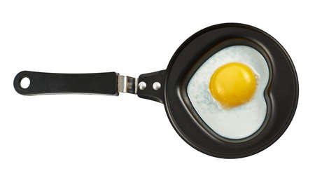 Heart shaped scrambled egg in a black pan isolated over white backgroundの写真素材