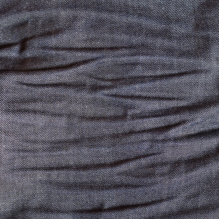 Crumpled jeans cloth fragment as a texture backgroundの写真素材