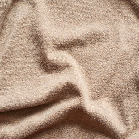 Creased beige cloth material fragment as a background textureの写真素材