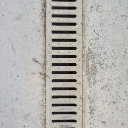 Drain grate in concrete floor as abstract background compositionの写真素材