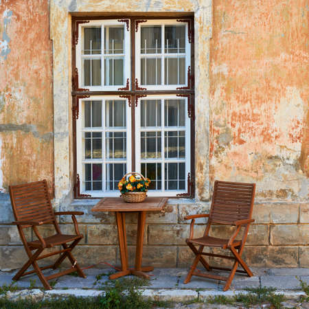 Two wooden chair and table in front of the old facade as outside dinner compositionの写真素材