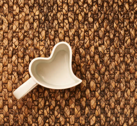 Heart shaped empty cup over the brown wicker surface, view aboveの写真素材
