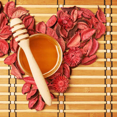 Heart shape made of potpurri around the jar of honeyの写真素材