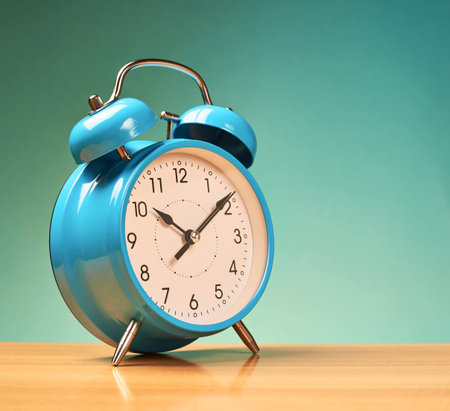 Blue alarm clock on the wooden surface against the blue background
