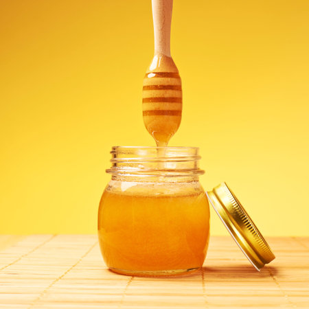 Composition of honey jar with the wooden dipper over it