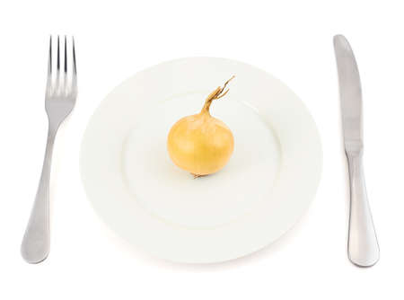 Onion over white ceramic dish plate with fork and knife isolated over the white backgroundの写真素材