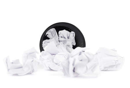 Office paper black trash bin, lying on its side next to crumpled paper, isolated over the white backgroundの写真素材