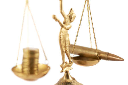 Metal two-pan scales statuette metal figure with the money on the one side and the bullet on the other oneの写真素材