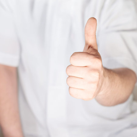 Thumbs up hand gesture against the white shirt, shallow depth of fieldの写真素材