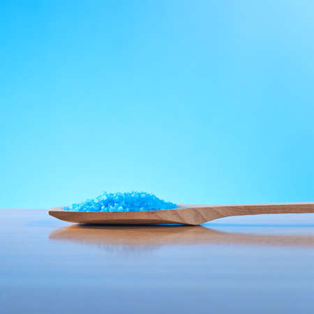 Spoon full of blue aromatic salt composition over the reflective surface and against the blue backgroundの写真素材