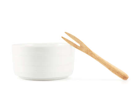 Small glazed white ceramic bowl with a tiny wooden fork, isolated over the white background, side viewの写真素材