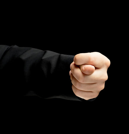 Caucasian male hand in a business suit, showing the offensive fig gesture sign, low-key lighting composition, isolated over the black backgroundの写真素材