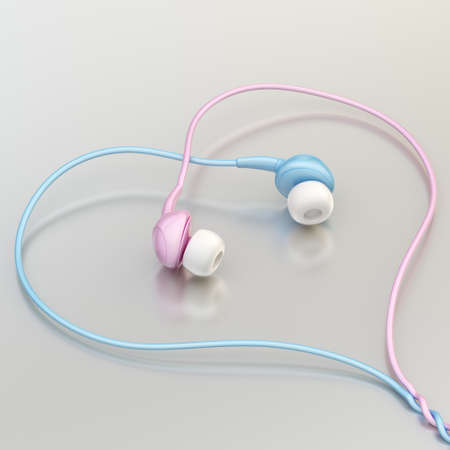 In-ear pink and light blue headphones forming a heart shape over the metal reflective surfaceの写真素材