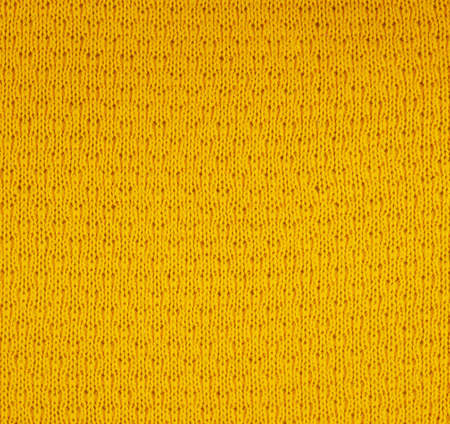 Fragment of a knitted yellow piece of cloth fabric as a background textureの写真素材