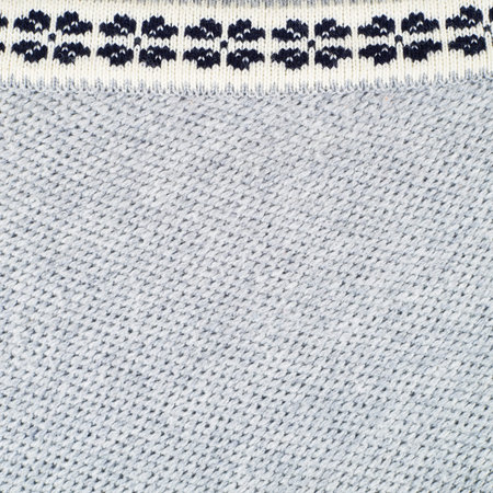 Fragment of a knitted gray blouse with the black and white ornament as a background composition