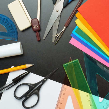 Black desk\'s surface covered with multiple stationery office supplies as a background back to...