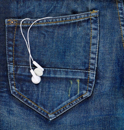 Pair of ear-in headphones in a back pocket of a navy blue denim jeans の写真素材