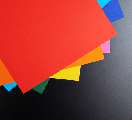 Colorful a4 paper sheets over the black surface as a background compositionの写真素材