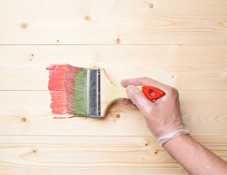 Process of starting to paint the wooden boards with the red paint brushの写真素材