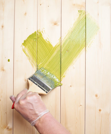Green yes tick symbol drawn with the wide brush over the polished pine wood boardsの写真素材