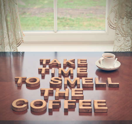 Take time to smell coffee quote made with the block wooden letters over the table, next to a cup of coffee, composition with tone image correctionの写真素材
