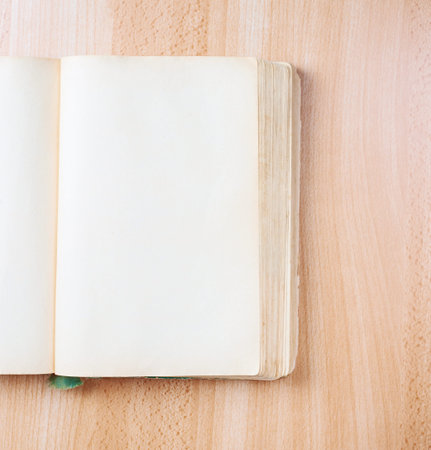 Composition of the opened old book with the empty pages over the wooden table