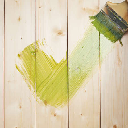 Green yes tick symbol drawn with the wide brush over the polished pine wood boardsの写真素材