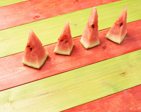 Multiple watermelon pieces over the background of the red and green painted wooden boardsの写真素材