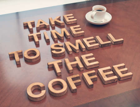 Take time to smell coffee quote made with the block wooden letters over the table, next to a cup of coffee, composition with tone image correctionの写真素材