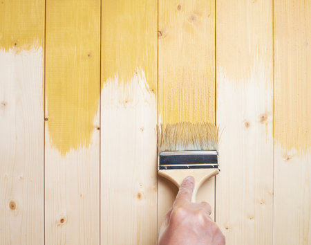 Process of painting the pine wood boards with the brush and the yellow paintの写真素材