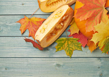 Orange pumpkin and maple leaves composition over the background made of green colored wooden boardsの写真素材