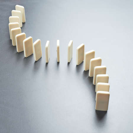 Domino\'s effect composition of a multiple domino bones placed in a row over the dark gray surfaceの写真素材