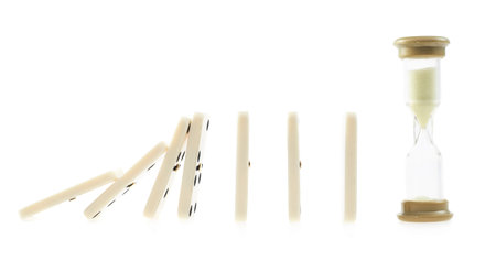 White domino bones pieces falling one after another on to the sandglass watches, composition...
