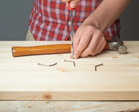 Screwing the screw after failing to hammer a nail to the wooden boards compositionの写真素材