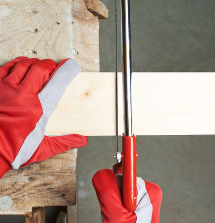 Sawing wooden pine board with the hand saw indoor composition, top view above foreshorteningの写真素材