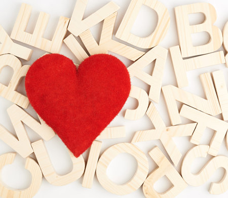 Red plush heart over the surface covered with the wooden letters as a background compositionの写真素材