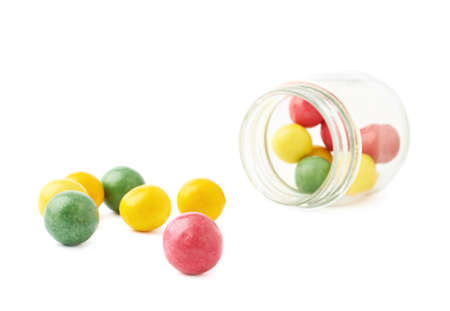 Multiple chewing gum balls next to a lying on its side glass jar, composition isolated over the white backgroundの写真素材