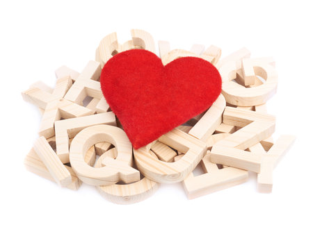 Passion for reading as a composition of the red heart over the pile of multiple wooden letters, isolated over the white backgroundの写真素材